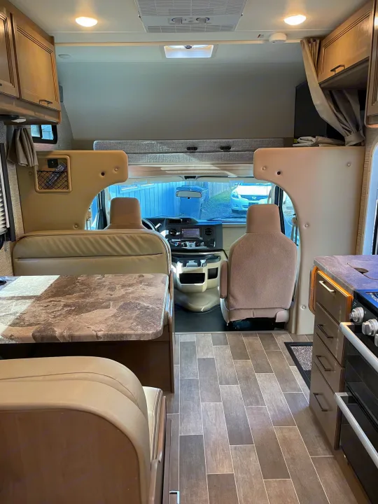 Explore this modern RV rental interior featuring a dinette, kitchen, and driver's cockpit.. Thor Magnitude GA22 2022