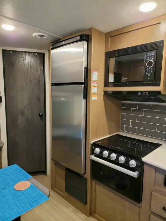 RV rental kitchen: Features a microwave, stove/oven, and stainless steel refrigerator in modern cabinetry.. Keystone Hideout 2021