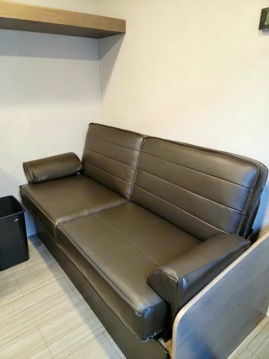 Overhead view of an RV rental interior: dark faux leather dinette with table, light textured walls, & wood-look floor.. Keystone Hideout 2021