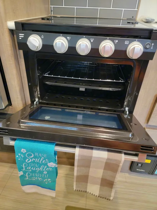 RV rental kitchen features a clean, compact black oven with its door open and controls on the side.. Keystone Hideout 2021
