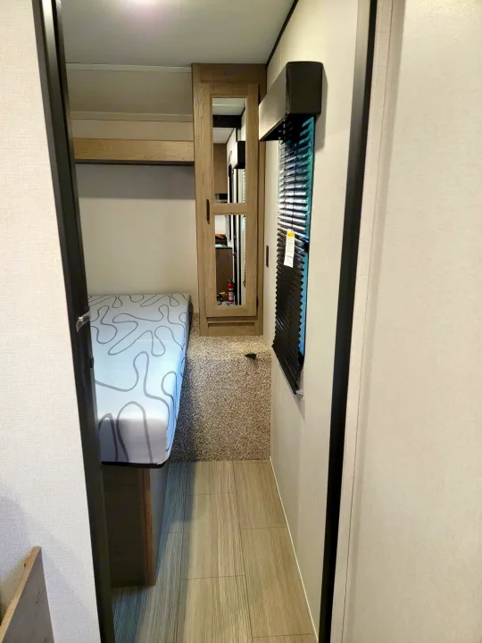 Cozy RV rental interior with overhead vent, wood cabinets, and a patterned cushion for lounge or sleeping.. Keystone Hideout 2021