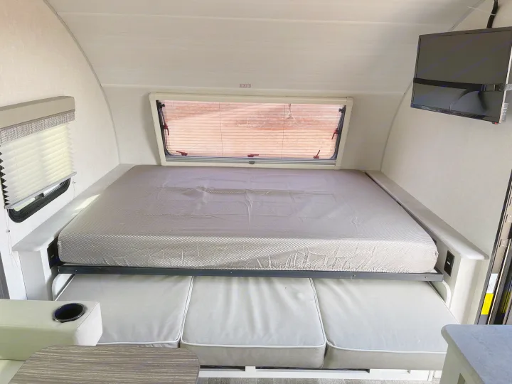 Inside an RV rental: a modern, versatile space with a bed that folds over a cozy dinette. Includes window & TV.. Forest River RPod193 2022