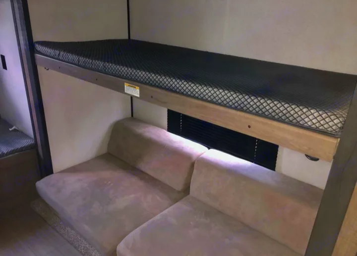 RV rental interior featuring a bunk bed over a plush sofa and window blinds, ideal for comfortable travel.. Keystone RV Hideout LHS 2021
