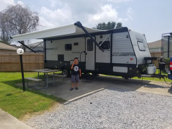 Boy at an RV rental travel trailer campsite with an extended awning.. Coachmen Viking 2019