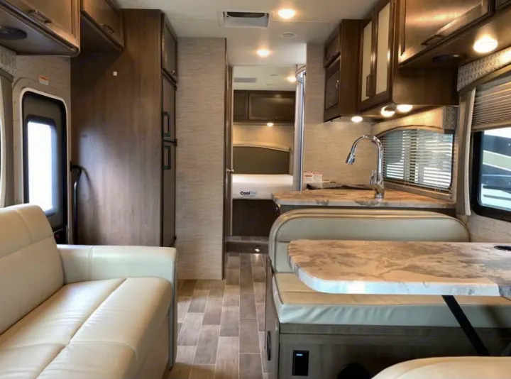 Inside your next RV rental: a modern living space with a kitchen, dinette, and bedroom, ready for your road trip comfort.. Thor Motor Coach Chateau 2021