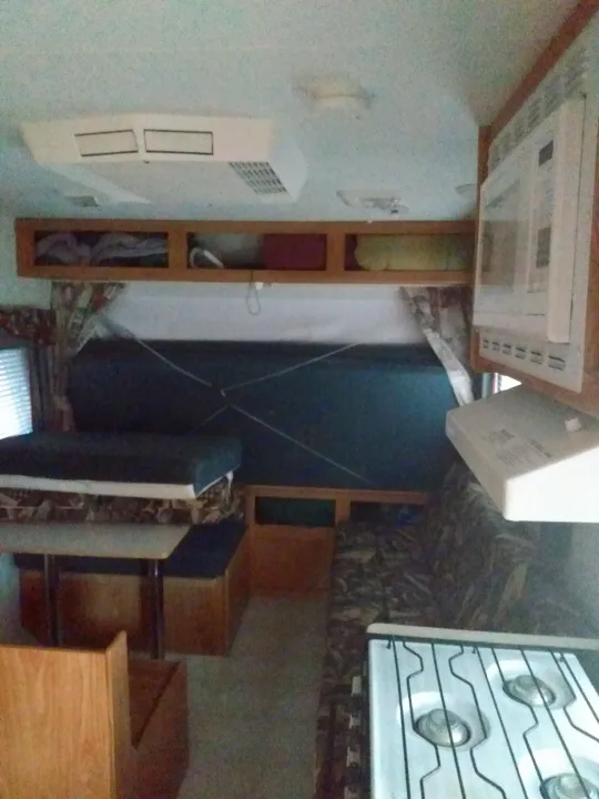 Spacious RV rental interior: dinette, bed, kitchen (stove, microwave), cabinets, AC, and sofa for comfortable living.. Sportsmen Coyote 2002