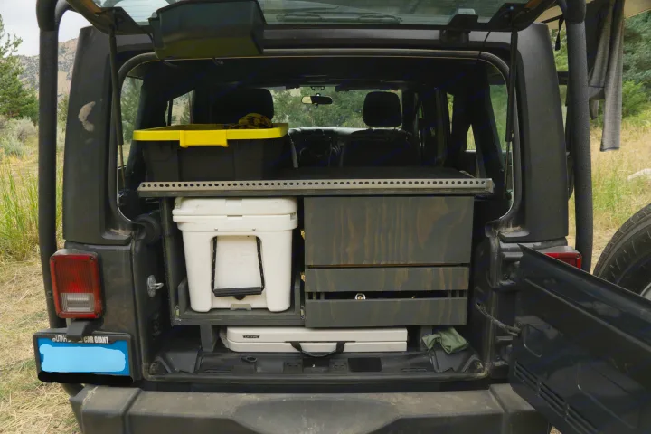 Rear of an SUV with custom camping storage: Yeti cooler, drawers, and bin. Ideal for RV rental adventures or overlanding.. Jeep Wrangler Unlimited 2018