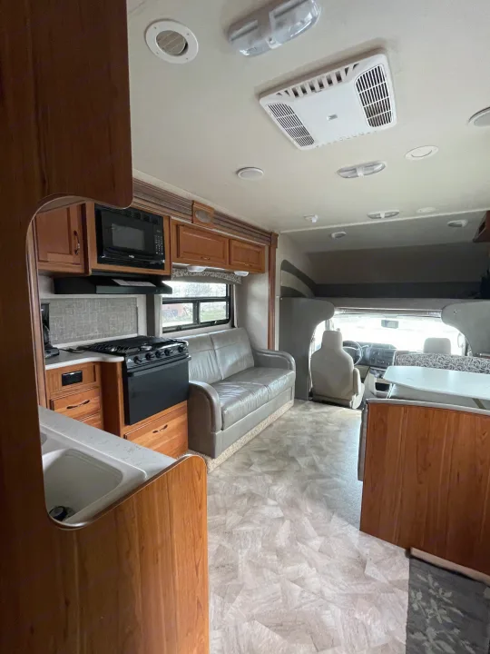Spacious rv rental interior, featuring a full kitchen, living area with a sofa, and front cabin views.. Jayco Redhawk 2016