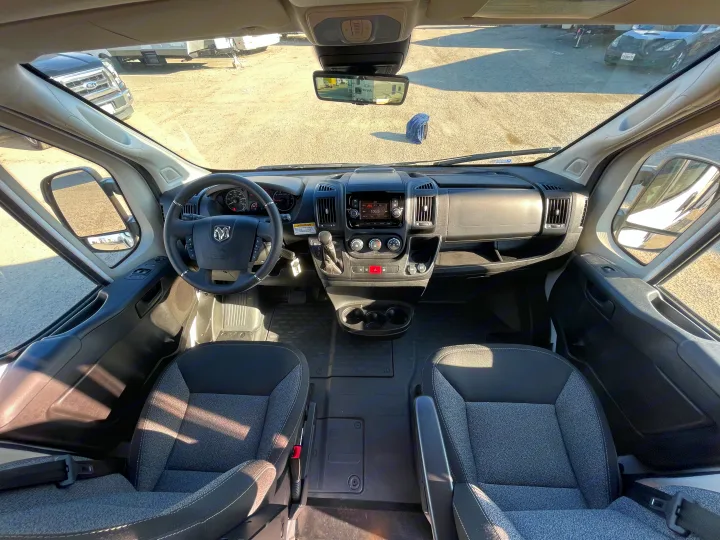 RV rental: Bright, wide-angle view of a camper van's cockpit, showing steering wheel, dashboard, and front seats.. Winnebago solis 2022