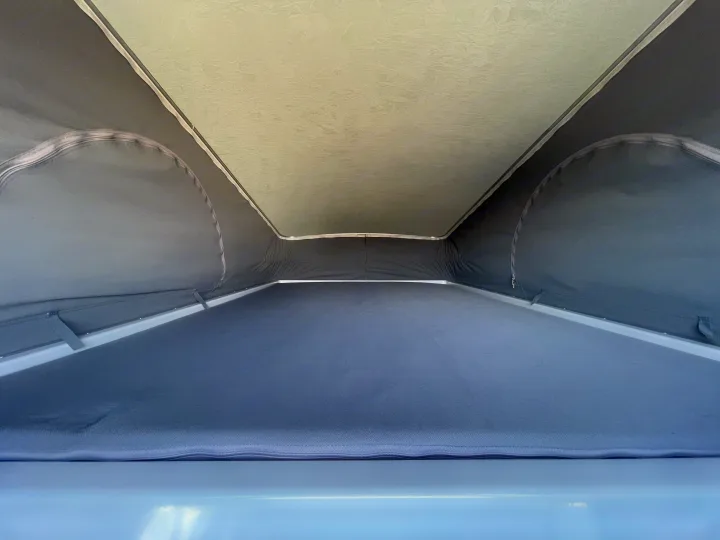 RV rental pop-top: Interior view of the bed area with grey fabric walls and a light, textured roof above.. Winnebago solis 2022