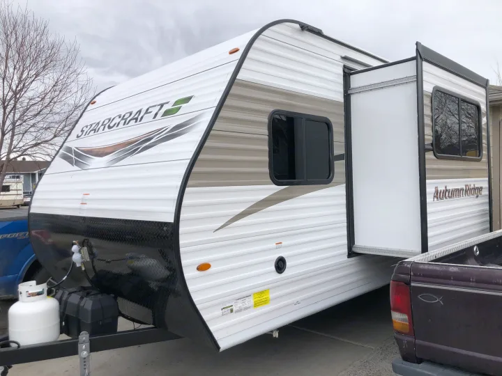 White Starcraft Autumn Ridge travel trailer parked, possibly an RV rental, with its side slide-out extended.. Starcraft Autumn Ridge BHS180 2022