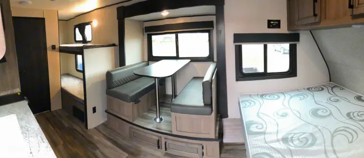 RV rental interior: bunk beds on left, dinette with table in center, and a main bed on right, offering comfort.. Starcraft Autumn Ridge BHS180 2022