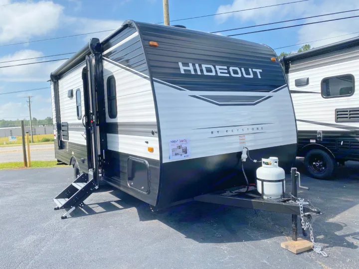 A sleek black and white Hideout by Keystone travel trailer, perfect for RV rental. Steps and propane tank visible.. Keystone RV Hideout 2022