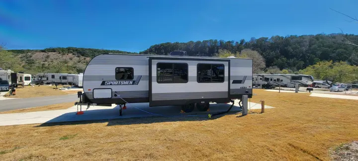 A Sportsmen travel trailer RV parked at a sunny campground. Consider this RV rental for your next outdoor adventure.. Sportsmen SE 2021