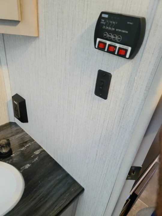 RV rental interior: countertop, sink, wall outlet, light switch, and RV control panel for tank levels/battery/water.. Heartland mallard 2022