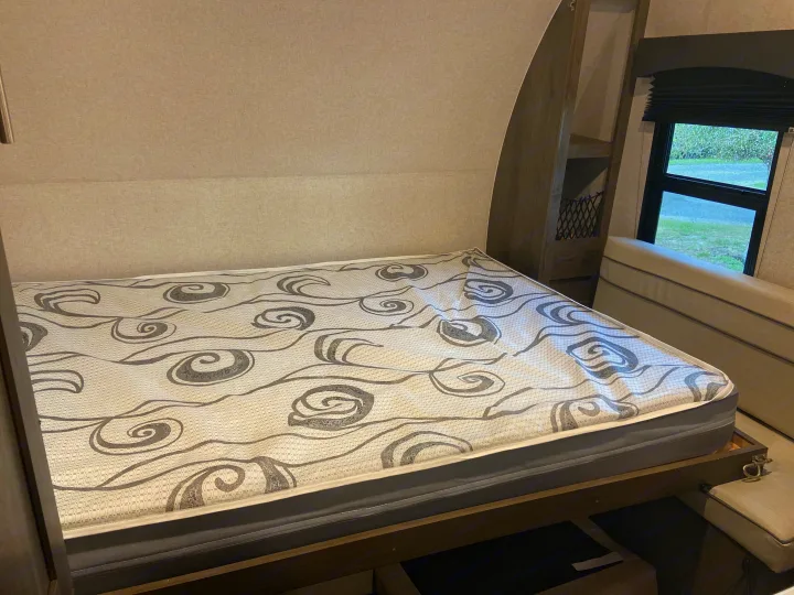 RV rental: Bed with grey patterned mattress, window, storage shelves, and under-bed storage for travel.. Clipper Other 2021