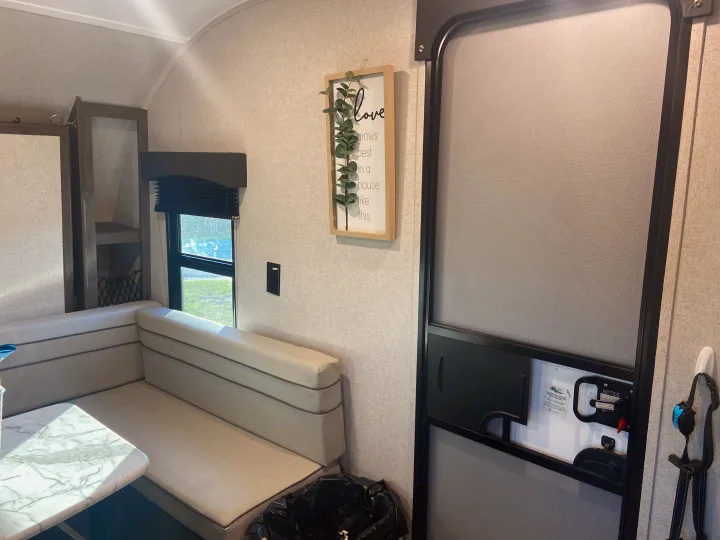 Cozy RV rental interior with a light-colored dinette booth, window with blinds, and main screen door.. Clipper Other 2021