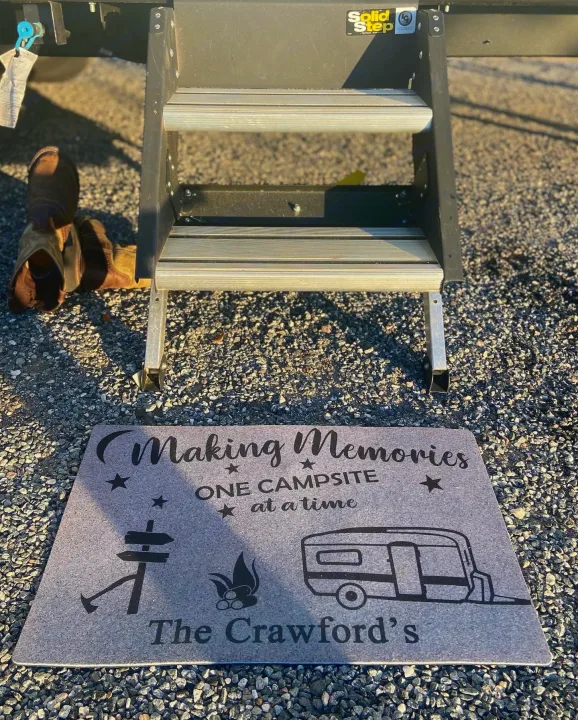 RV rental steps & doormat on gravel. Custom mat reads 'Making Memories ONE CAMPSITE at a time'. Camping boots nearby.. Clipper Other 2021