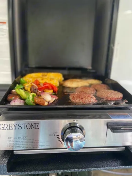 Enjoy an RV rental adventure with outdoor cooking! Sizzling burgers, corn, and colorful veggies grill on a portable GREYSTONE griddle.. Clipper Other 2021