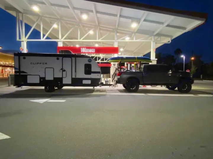 This RV rental and truck, packed with a paddleboard and bike, refuels at a Wawa gas station at night.. Clipper Other 2021