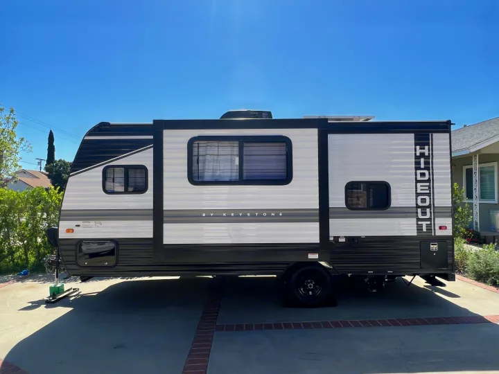 Sleek white & black Keystone Hideout travel trailer parked in a driveway. Consider this RV for your next rental adventure!. Keystone RV Hideout 2022