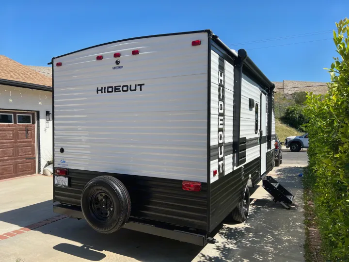 Rear view of a new white and black Hideout travel trailer parked on a driveway, ideal for an rv rental getaway.. Keystone RV Hideout 2022