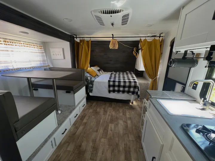 This RV rental interior offers a cozy dining booth, a comfortable bed, and a compact kitchen. Ideal for mobile living.. Keystone RV Hideout 2022