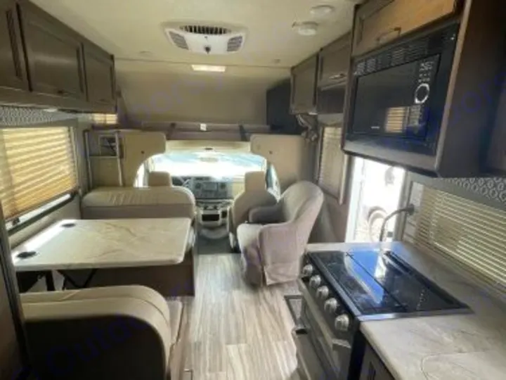 This spacious RV rental interior features a modern kitchen, dining table, and living space, looking towards the cockpit.. Thor Freedom Elite 2021