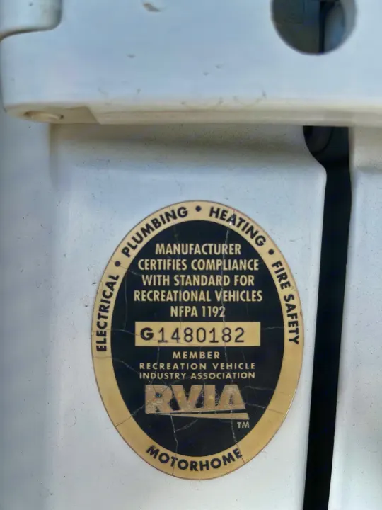 Close-up of an rv rental's RVIA certification, detailing compliance for electrical, plumbing, heating, and fire safety.. Sportsmobile Custom Design 2013