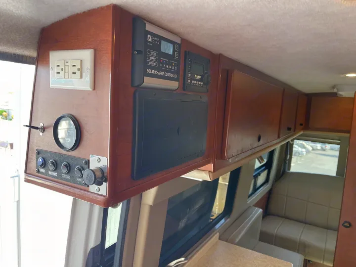 RV rental interior: wood overhead console with solar, power outlets, switches, and storage compartments.. Sportsmobile Custom Design 2013