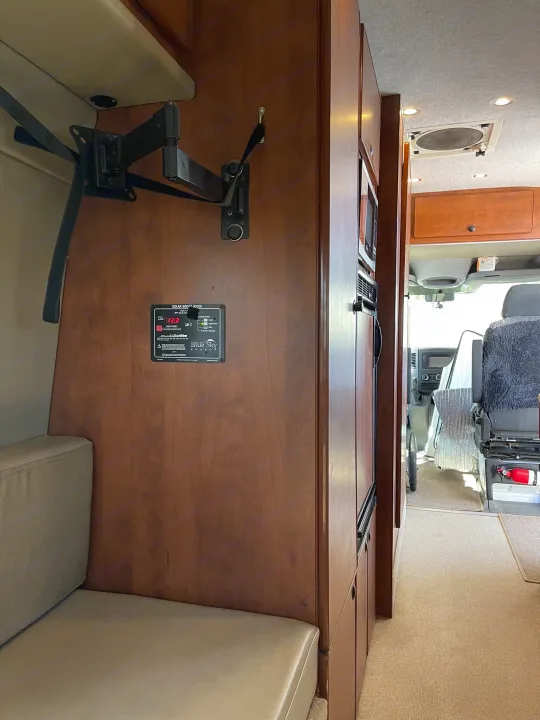 Inside an RV rental: a TV mount, solar monitor, fridge, and seating area. Ready for your next adventure.. Sportsmobile Custom Design 2013