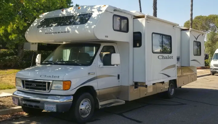 White Winnebago Chalet RV rental with extended slide-outs, parked on a sunny street.. Winnebago Chalet 2007