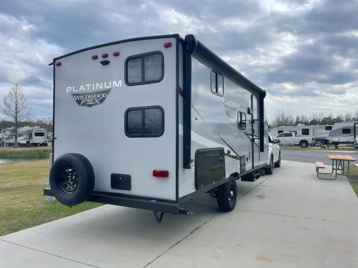 A gray Platinum Wildwood FSX travel trailer, ideal for an rv rental, is parked on a concrete pad at an RV park.. Forest River 178BHSKX 2022