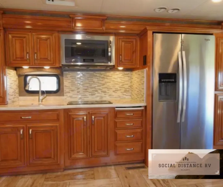 Inside a modern RV kitchen, complete with stainless steel appliances, ample wood cabinets, and a stylish tile backsplash. Ideal for RV rental.. Thor Motor Coach Venetian 2017