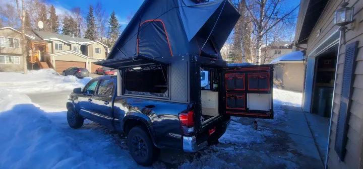 Black Toyota Tacoma with an Alucab pop-up truck camper and rooftop tent, showing an RV rental setup ready for adventure.. Toyota Tacoma 2022