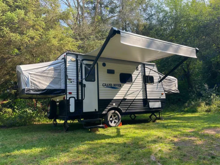 Enjoy camping! This RV rental is a hybrid travel trailer with pop-out beds & an awning, set up on grass among trees.. Forest River Other 2019