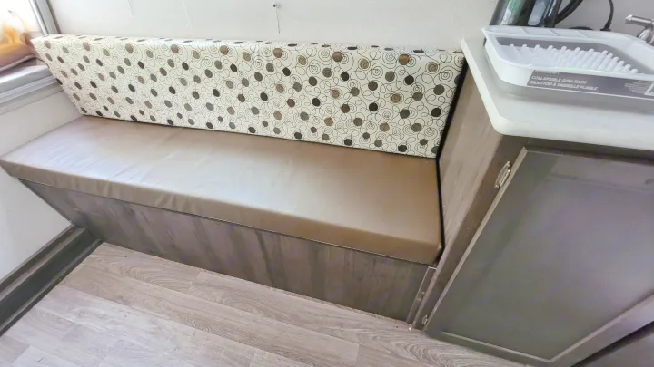 RV rental dinette with patterned back cushions, tan seat, and under-seat storage. A dish rack is on the adjacent counter.. Forest River Other 2019