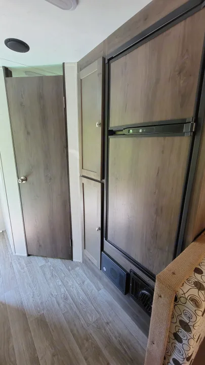 RV rental interior features wood-grain cabinets, hidden refrigerator, laminate flooring, and a patterned bed.. Forest River Other 2019