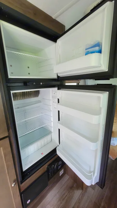 Two compact RV rental refrigerators, doors open, revealing organized shelves & a freezer for travel.. Forest River Other 2019