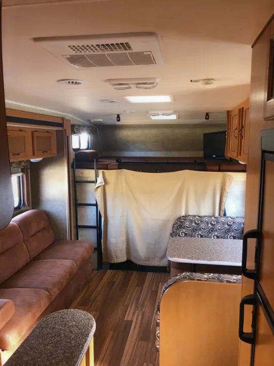 This RV rental offers a cozy interior with bunk beds, a living area, and a dining booth for comfortable travel.. Coachmen Freelander 2014