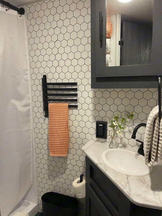 Modern RV rental bathroom features white hex tiles, black vanity, and sleek fixtures, offering comfort on the go.. Forest River 178BHSKX 2022