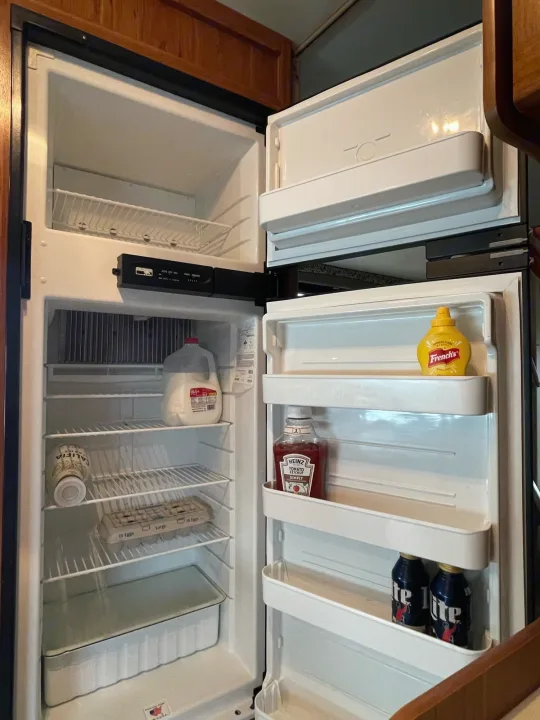 RV rental fridge shows milk, eggs, condiments, and drinks inside, plus an empty freezer shelf.. Jayco Redhawk 2016
