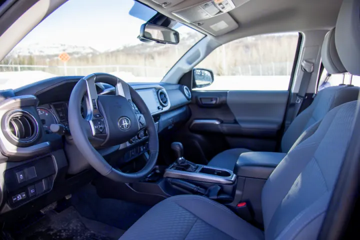 Spacious car interior with steering wheel, dashboard, and front seats. Excellent for your next RV rental journey.. Toyota Tacoma 2022
