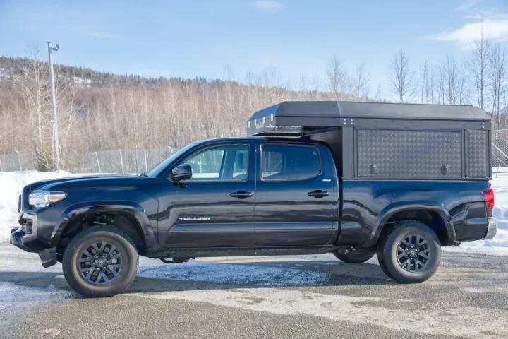 This black Toyota Tacoma pickup truck, equipped with a heavy-duty truck bed camper, is ideal for an RV rental adventure.. Toyota Tacoma 2022