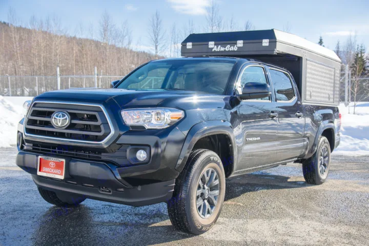 Black Toyota Tacoma overland rig with Alu-Cab camper, perfect for an RV rental adventure.. Toyota Tacoma 2022