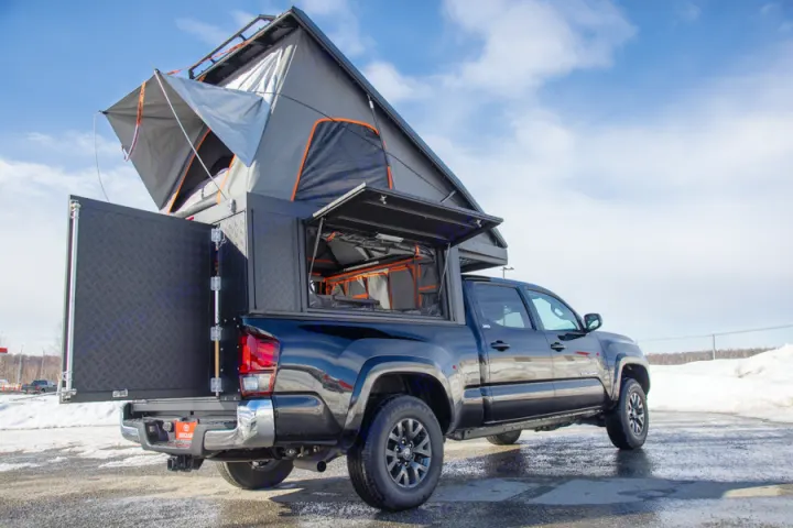 Explore the outdoors! This black pickup truck features a pop-up rooftop tent and truck camper, ideal for RV rental adventures.. Toyota Tacoma 2022