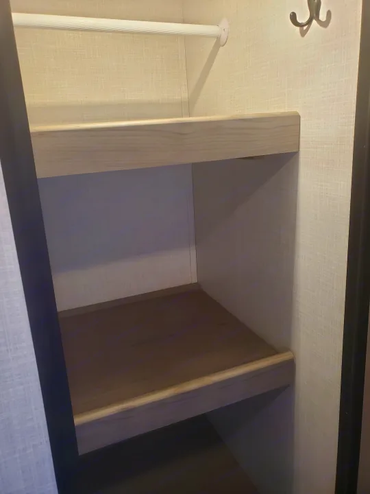 An RV rental closet featuring upper shelves, a hanging rod, and hooks, providing compact, organized storage.. Coleman 2455bh 2022