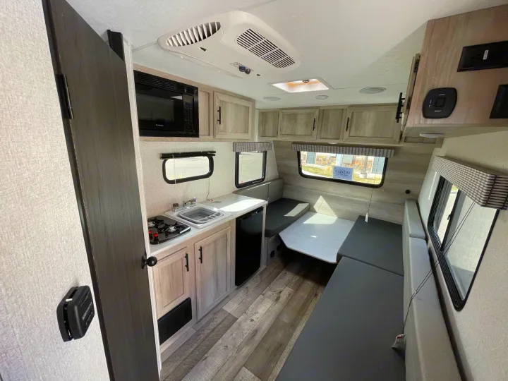 RV rental interior: a compact kitchenette with stove/sink, dinette area, and wood flooring.. Sportsmen Classic 2022