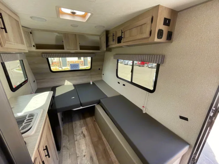 Inside this RV rental: functional dinette converts to a sleeping area, compact kitchenette, and overhead cabinets for storage.. Sportsmen Classic 2022