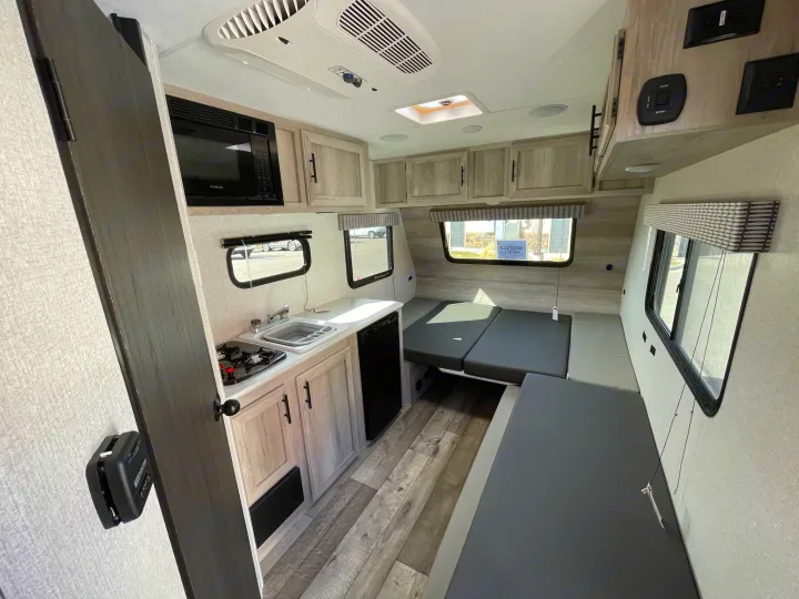 Explore this RV rental's cozy interior, featuring a compact kitchen, convertible dinette, and overhead storage.. Sportsmen Classic 2022